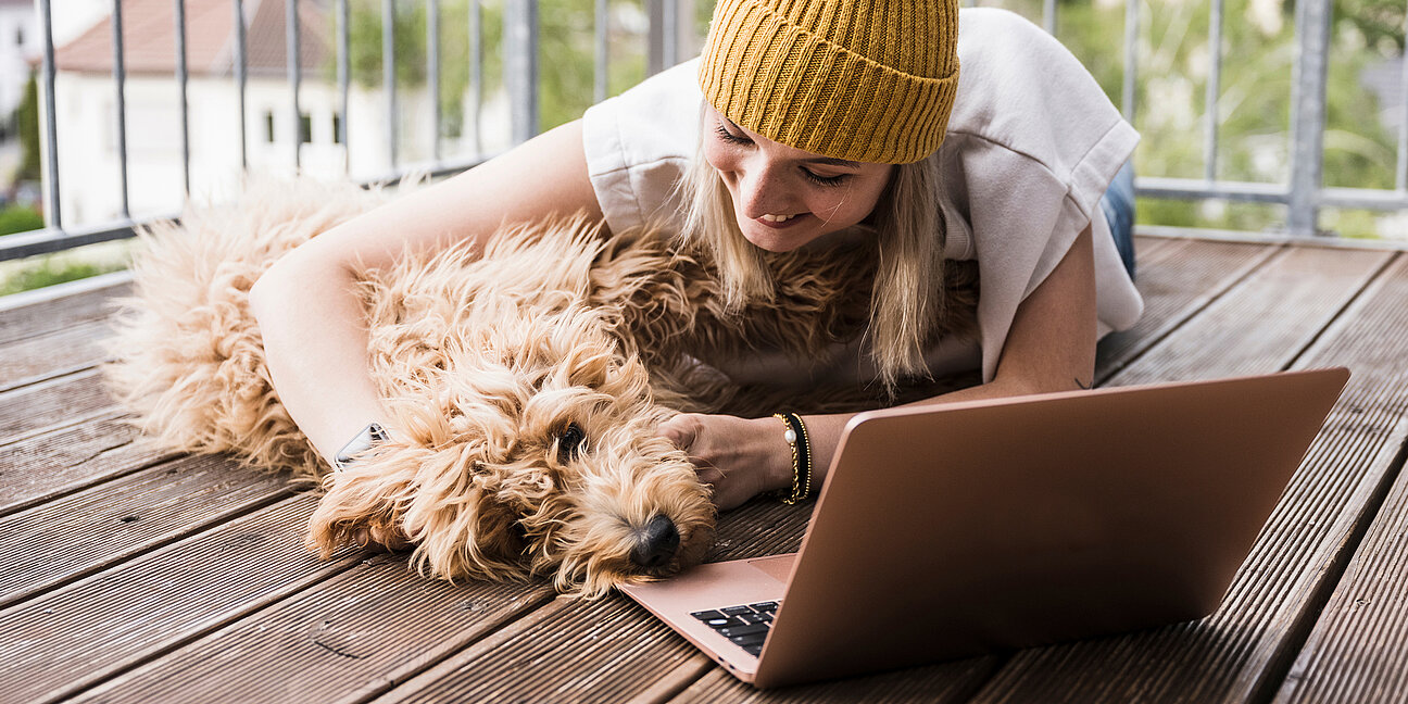 Frau mit Hund freut sich am Laptop