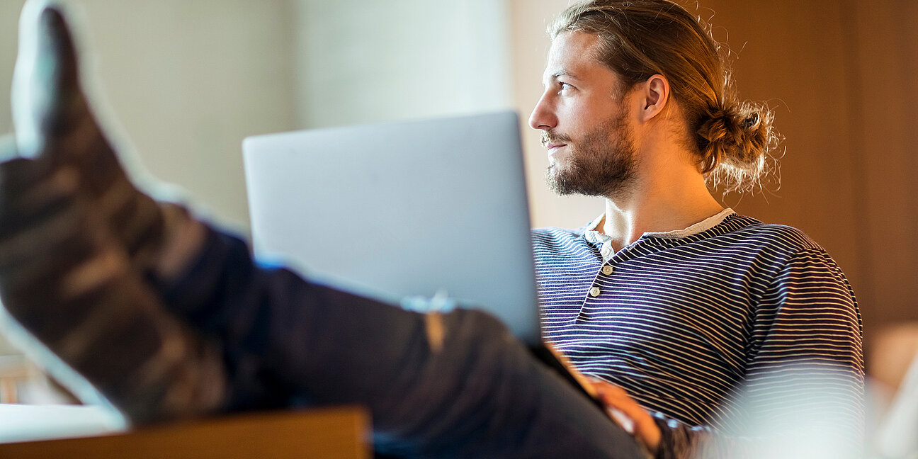 Porträt eines nachdenklichen jungen Mannes am Laptop